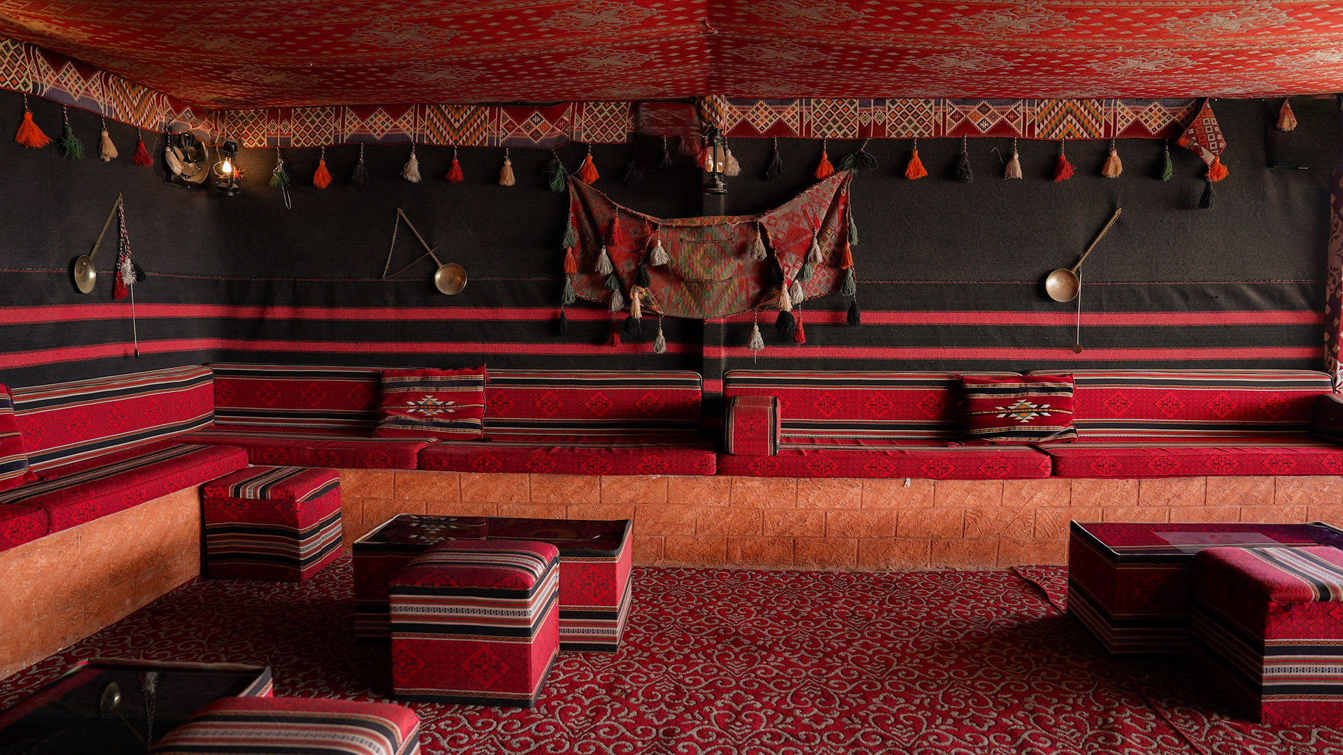 Bedouin majlis seating with red cushions and tassels on the rooftop