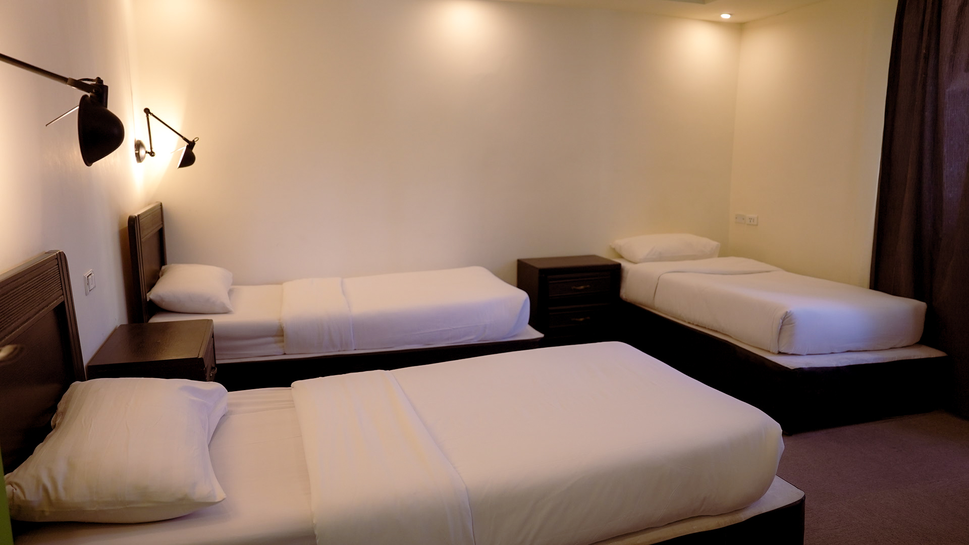 Triple room with three single beds and minimal decor