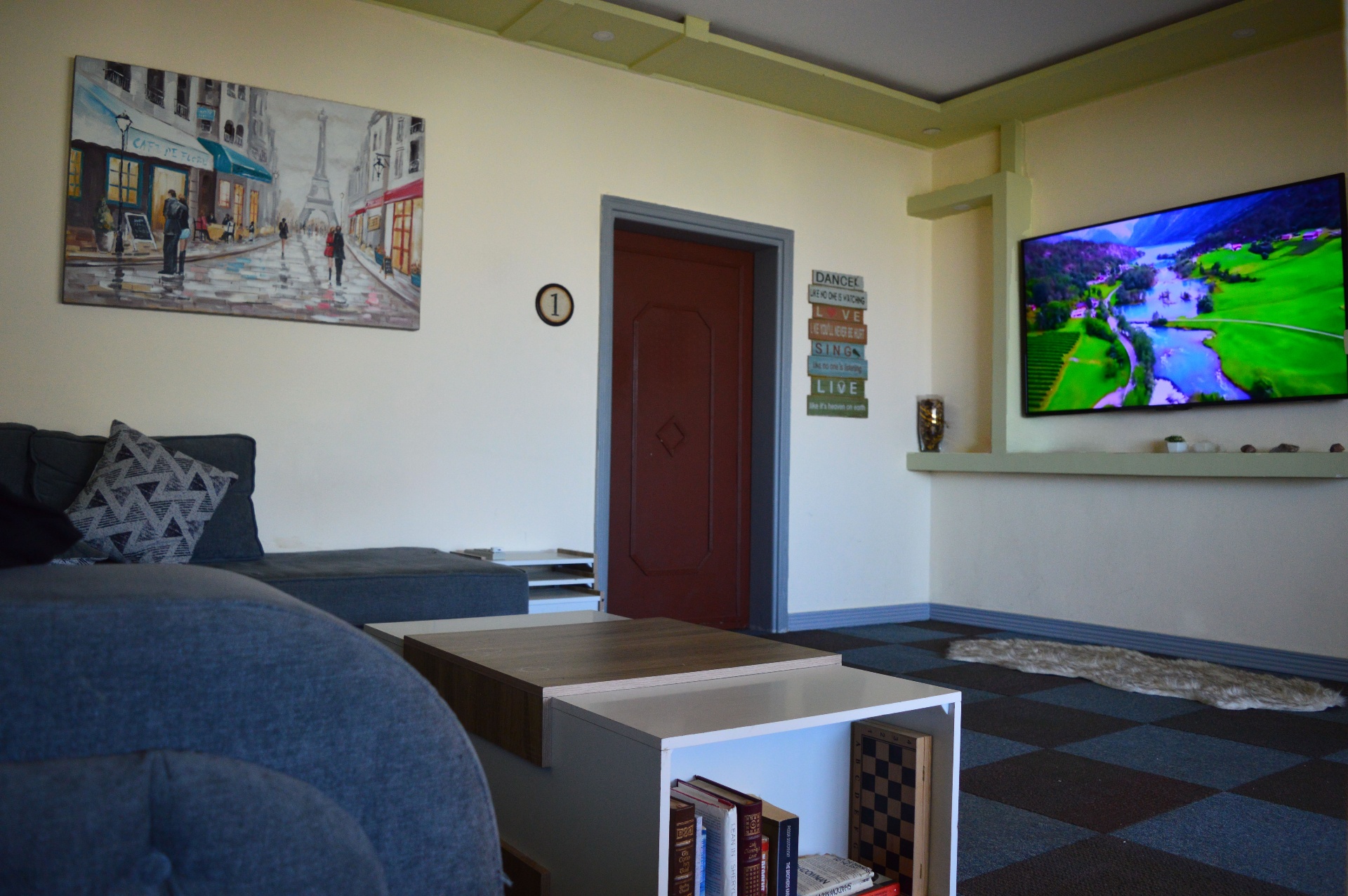 TV lounge with wall-mounted screen and Paris canvas