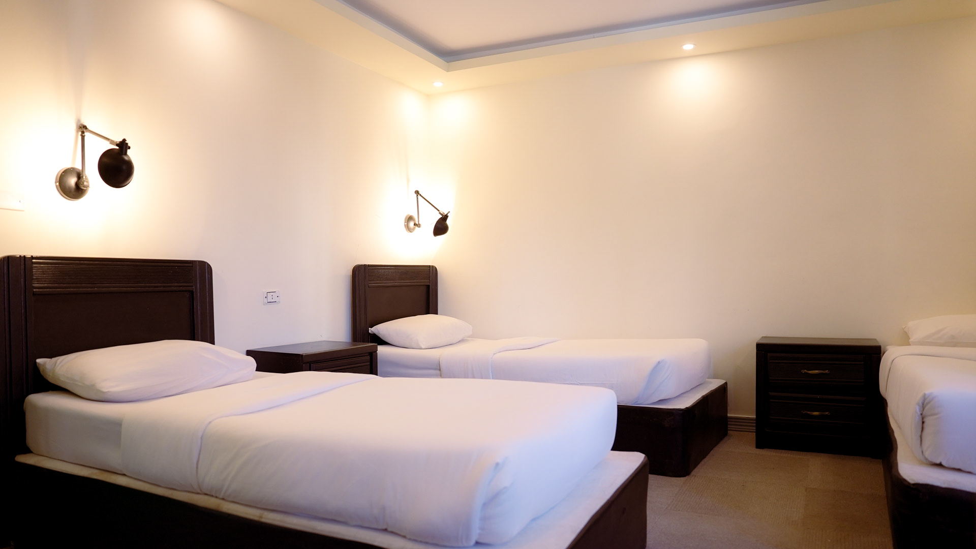 Twin room with three single beds and bedside tables