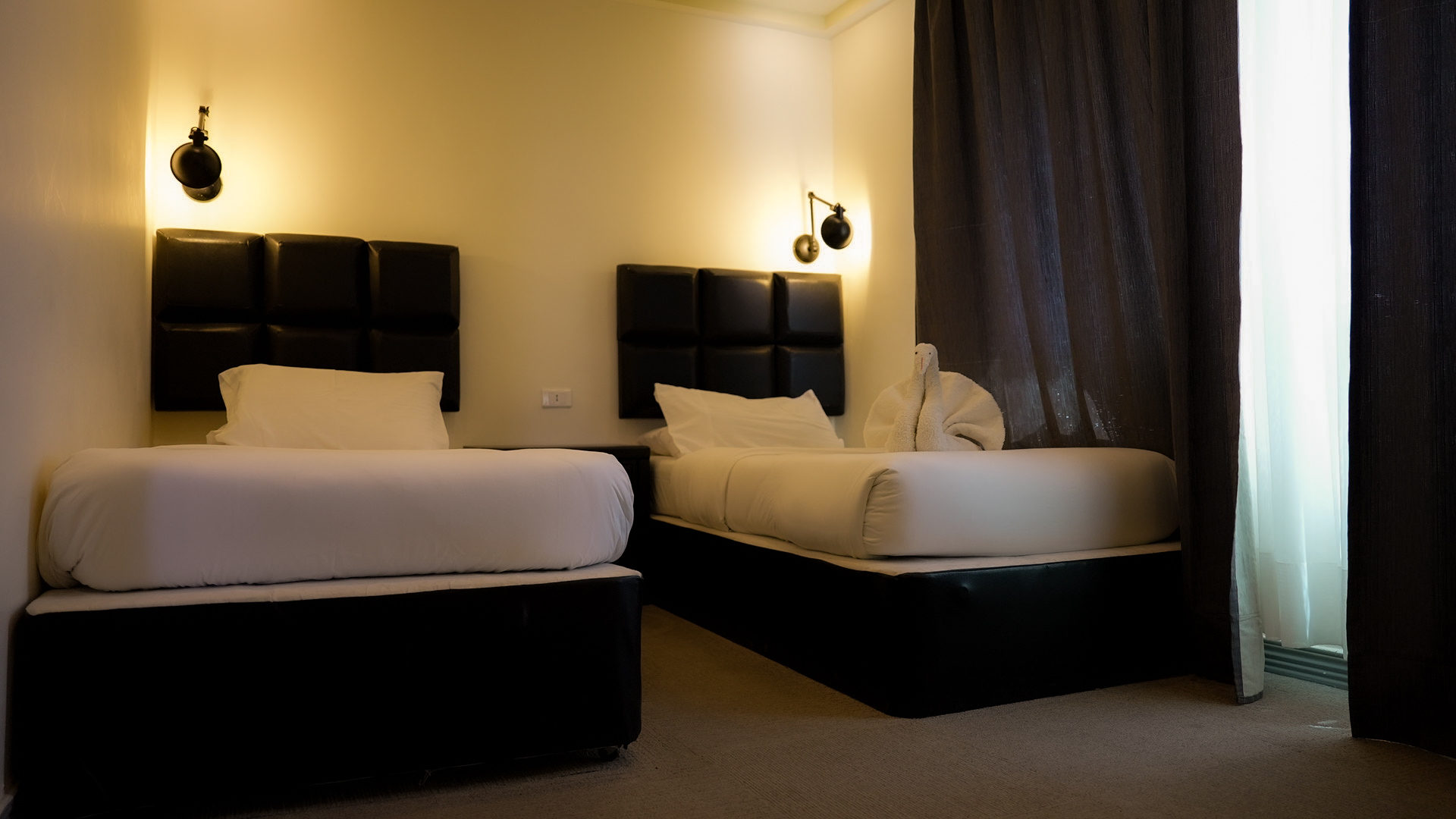 Twin room with two single beds, leather headboards and warm sconces